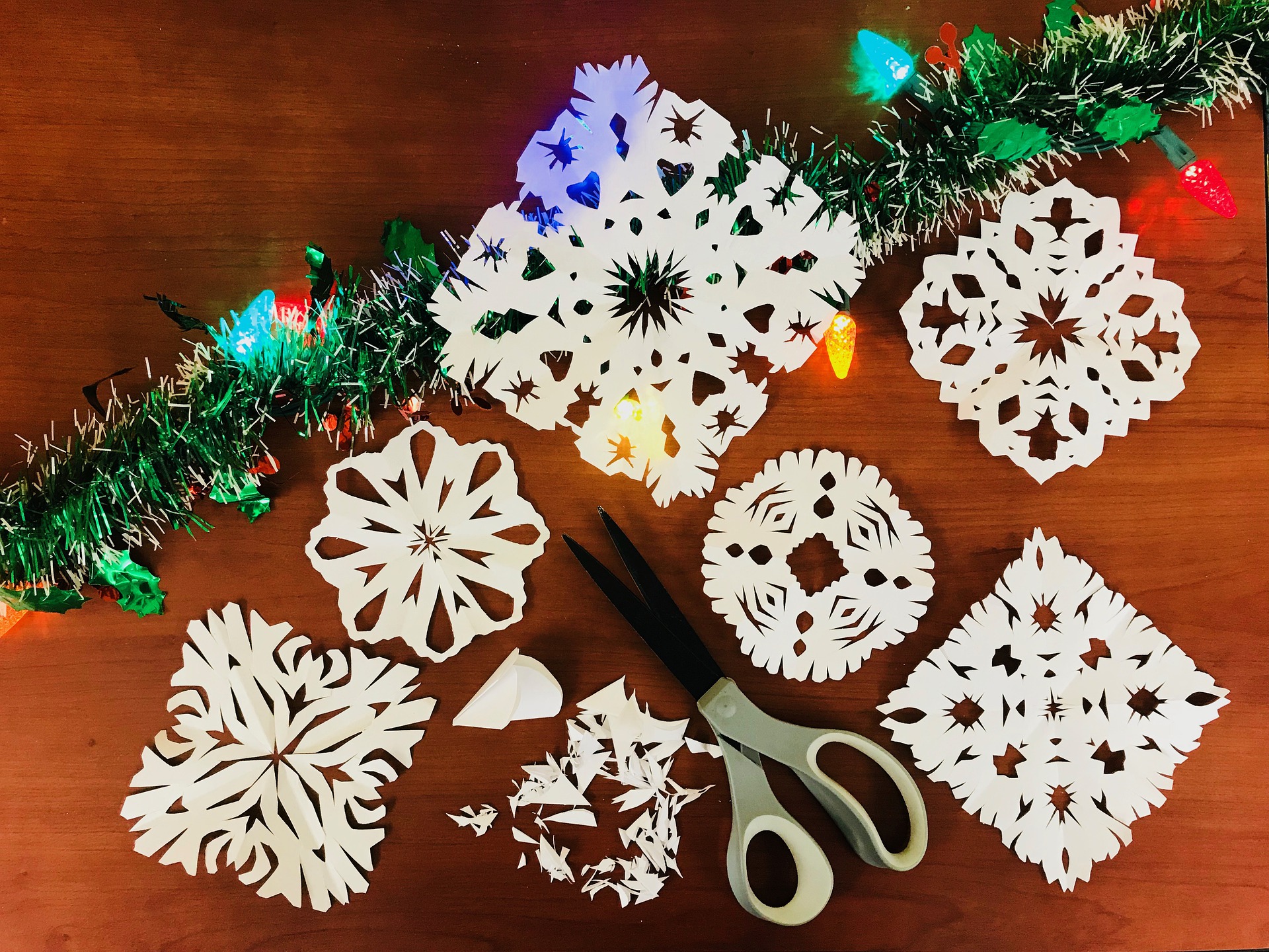 paper snowflakes and scissors next to a garland