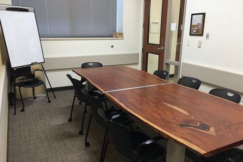 Main Library's Conference Room C equipped with a conference table, chairs, and a paper flipboard