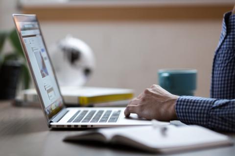 Person using laptop mousepad with coffee cup in background