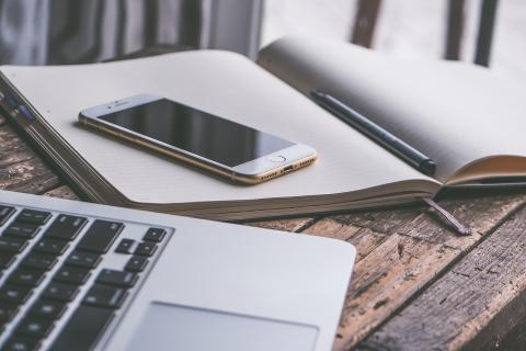 laptop, smartphone, and open notebook on table