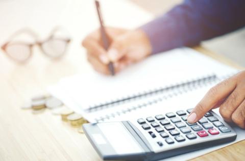 A person writing on paper and using a calculator