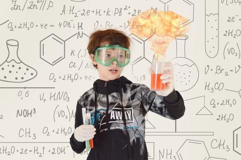 boy with safety goggles holds science beakers
