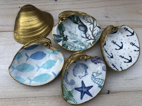 small half clamshells with decoupage navy blue fish, starfish, and anchors. Clamshells have a vibrant gold border and backing.