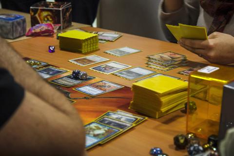 A group of people sitting around a table playing the card game Magic the Gathering.