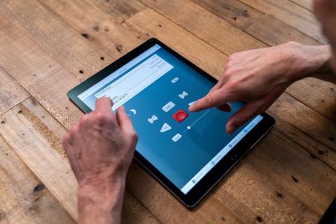 BARD Mobile application on a tablet. A hand is pressing the play button.