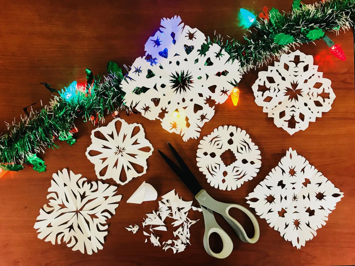 paper snowflakes and scissors next to a garland