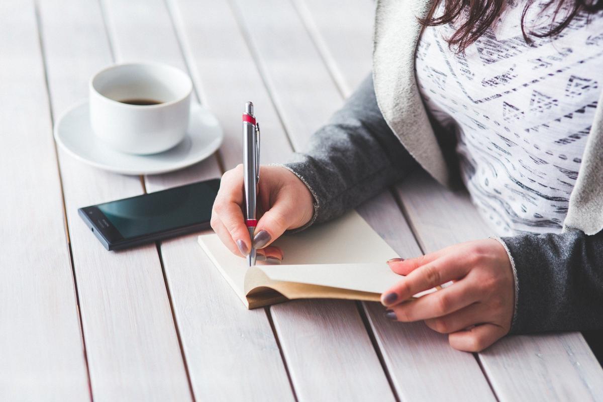 Woman writing in notebook with pen