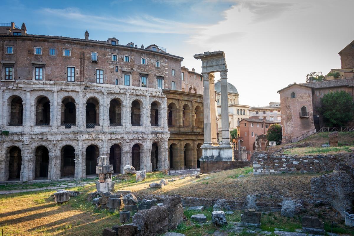 Roman ruins next to a small old graveyard and brick buildings in Italy