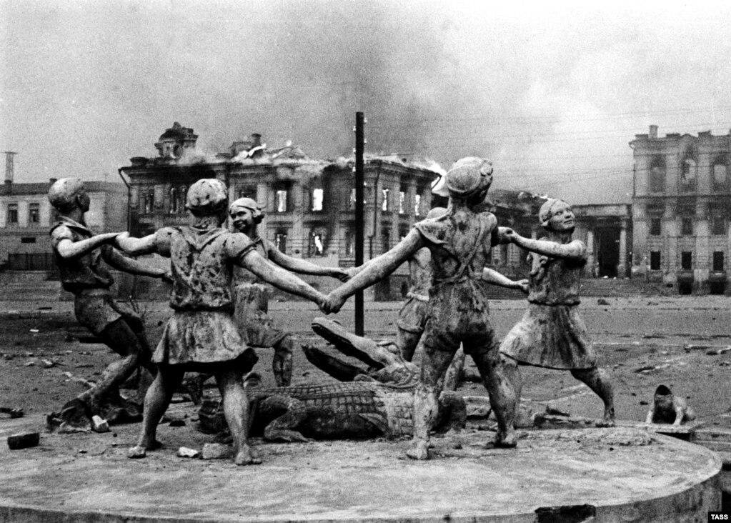 statue of girls playing, and building on fire in background