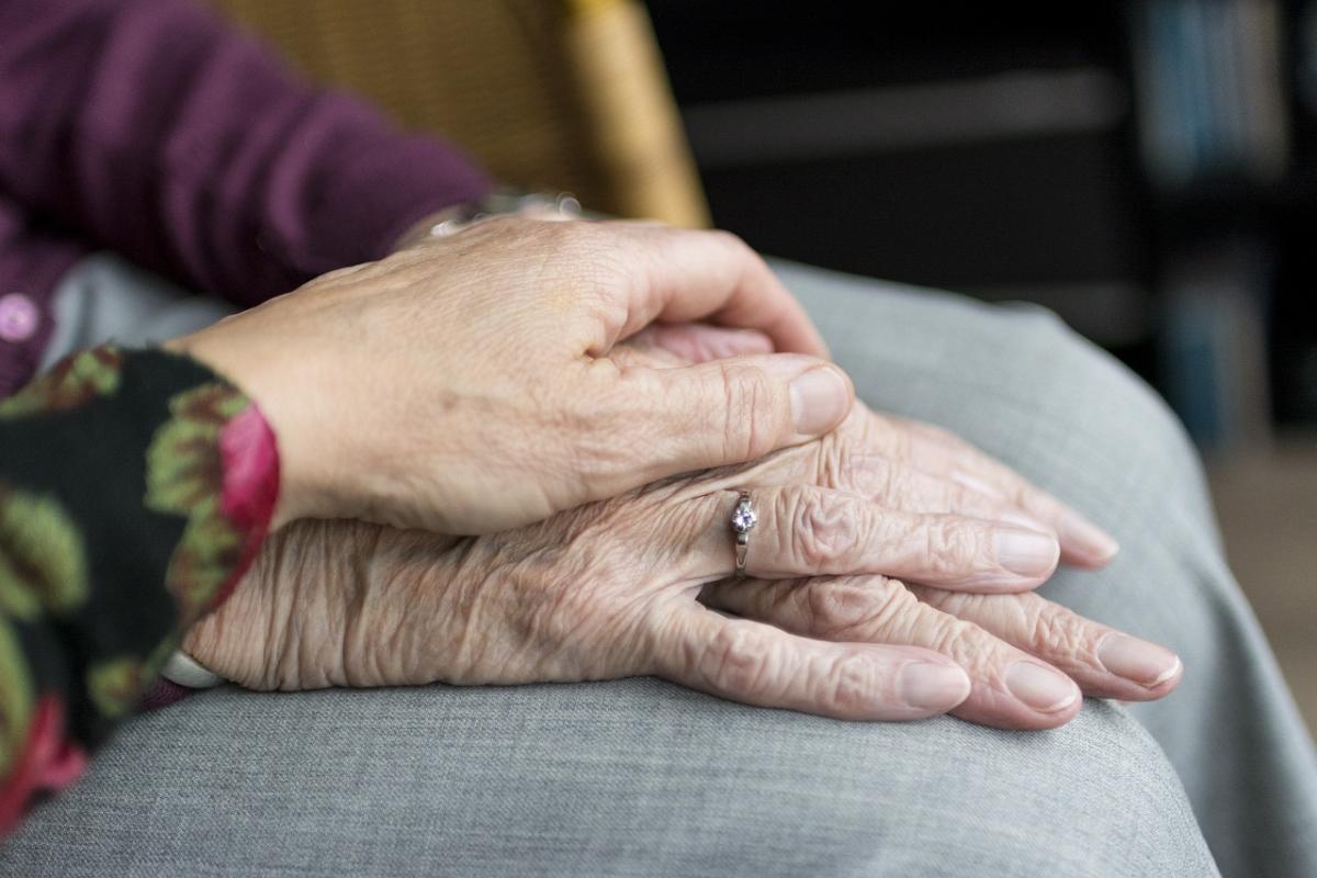 younger hand on top of older person's hands