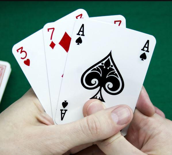 Two hands holding playing cards. 